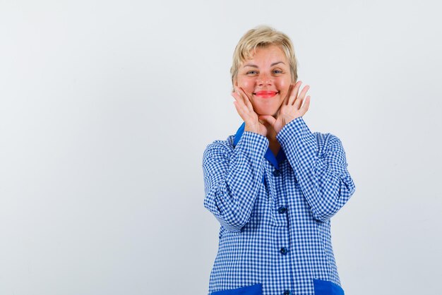 La giovane donna sorridente sta mettendo le mani sulle guance su sfondo bianco