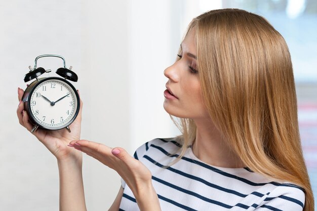 La giovane donna sorridente tiene l'orologio nero