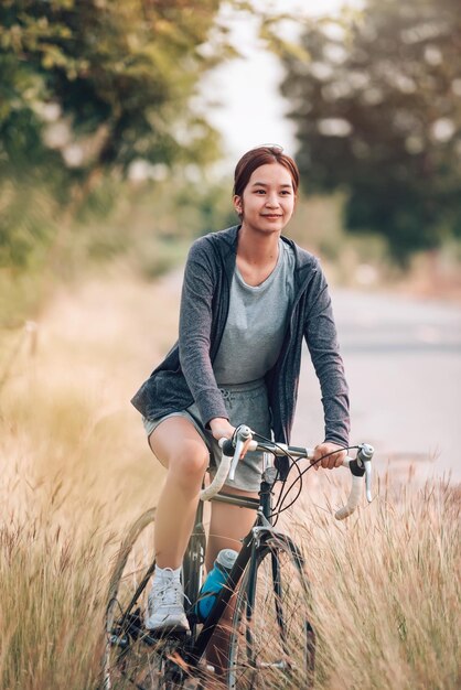 La giovane donna sportiva asiatica guida la bicicletta per l'esercizio e la ricreazione all'aperto sul concetto di trasporto freetimeEco