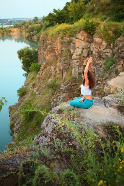 La giovane donna sta praticando yoga vicino al fiume