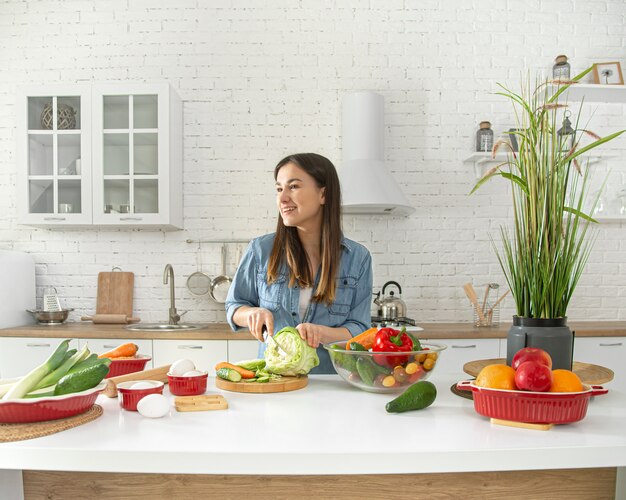 la giovane donna sta preparando un'insalata in cucina.