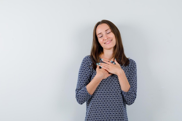 La giovane donna sta sognando unendo le mani sul petto su sfondo bianco