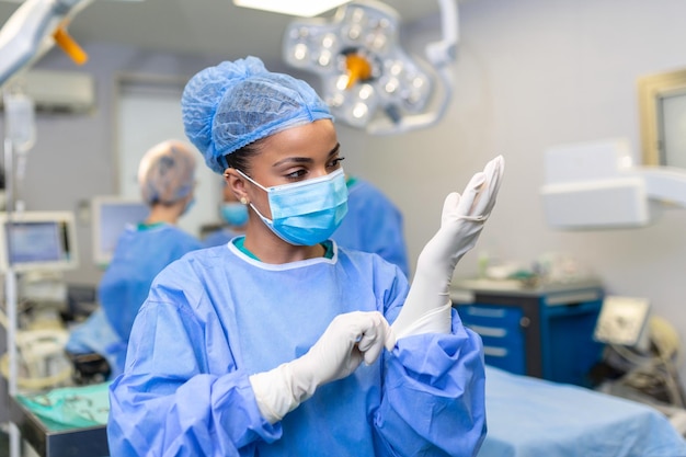 La giovane dottoressa si prepara per l'intervento chirurgico indossa guanti chirurgici blu in un cappotto e una maschera
