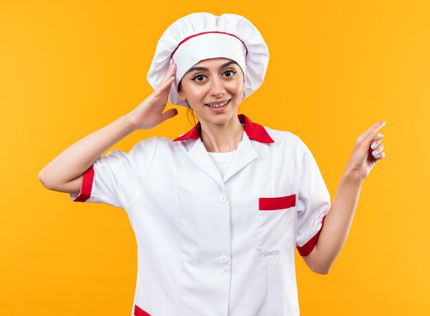 La giovane e bella ragazza sorpresa in uniforme da chef punta a lato