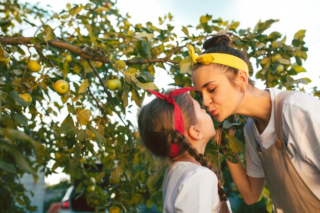 La giovane famiglia felice durante la raccolta delle mele in un giardino all'aperto