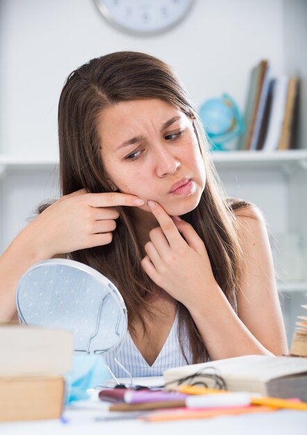 La giovane femmina sta spremendo un brufolo prima di fare il trucco