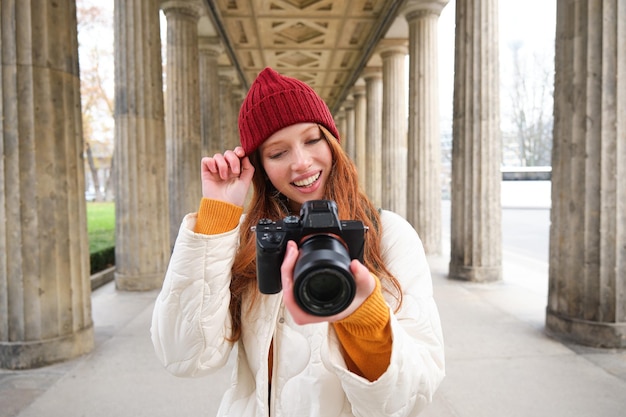 La giovane fotografa rossa fa riprese di stile di vita nel centro della città, scatta foto e sorride