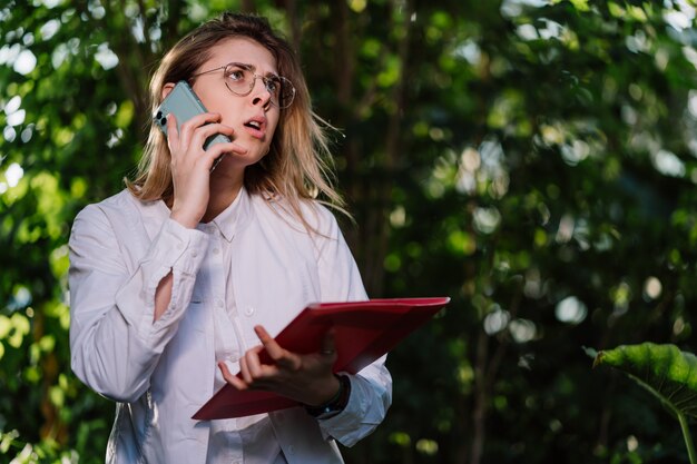 La giovane ingegnere agricolo femminile fa una chiamata in serra.