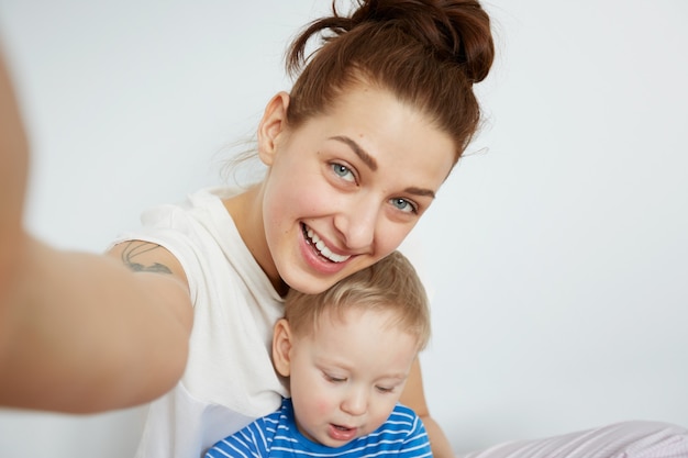 La giovane madre con il suo piccolo figlio di un anno vestito in pigiama sta proponendo