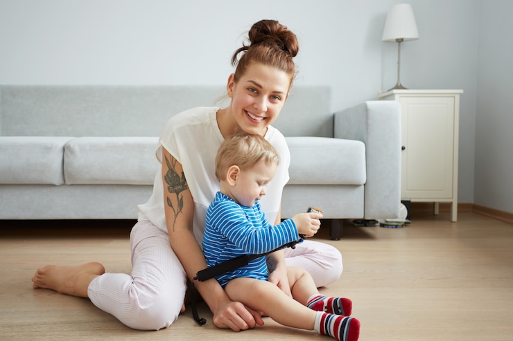 Foto gratuito la giovane madre con il suo piccolo figlio di un anno vestito in pigiama sta proponendo