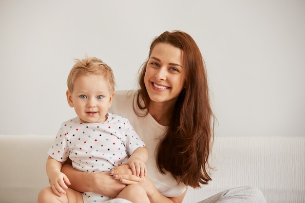 La giovane madre con il suo piccolo figlio di un anno vestito in pigiama sta rilassando