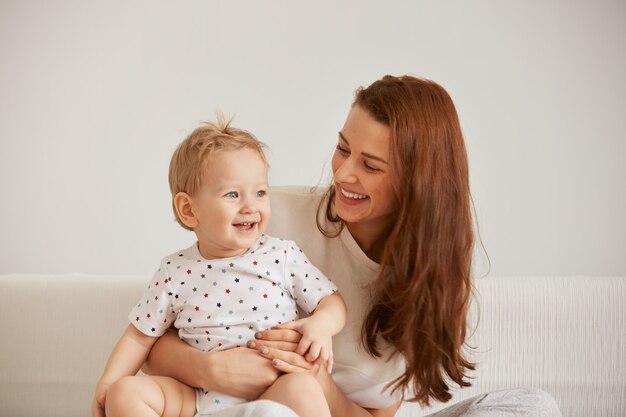 La giovane madre con il suo piccolo figlio di un anno vestito in pigiama sta rilassando