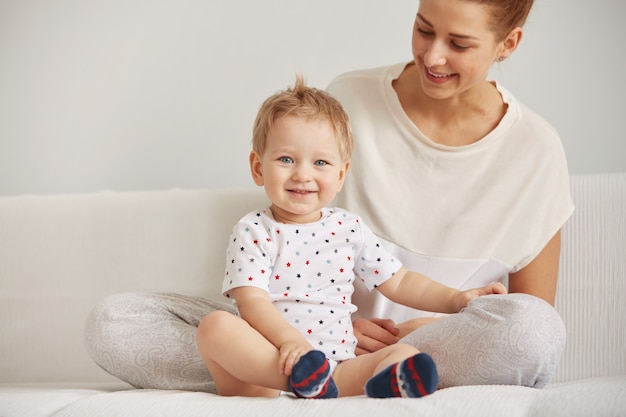 La giovane madre con il suo piccolo figlio di un anno vestito in pigiama sta rilassando