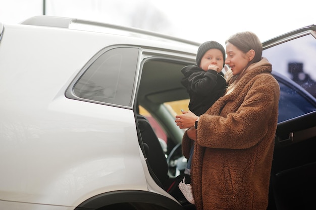 La giovane madre e il bambino stanno vicino alla loro auto suv Concetto di guida di sicurezza