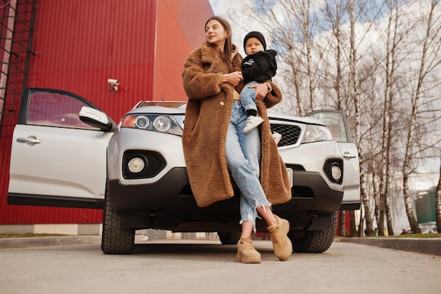 La giovane madre e il bambino stanno vicino alla loro auto suv Concetto di guida di sicurezza