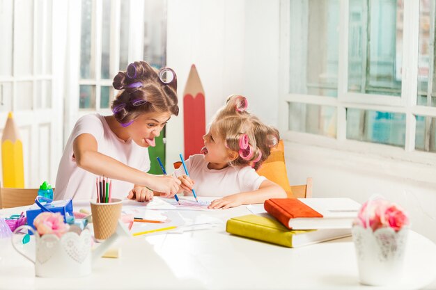 La giovane madre e la figlia piccola disegnano con le matite a casa