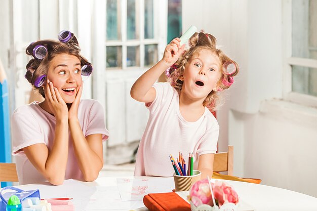 La giovane madre e la sua piccola figlia che disegnano con le matite a casa