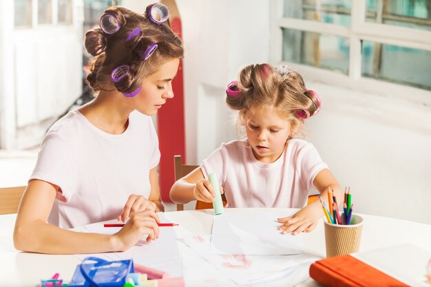 La giovane madre e la sua piccola figlia che disegnano con le matite a casa