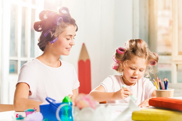 La giovane madre e la sua piccola figlia che disegnano con le matite a casa