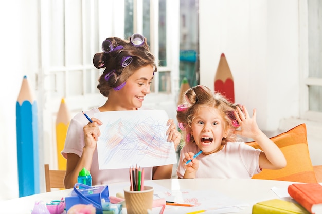 La giovane madre e la sua piccola figlia che disegnano con le matite a casa