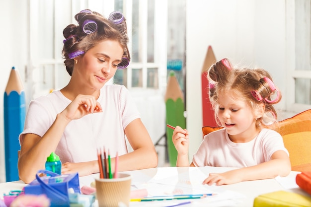 La giovane madre e la sua piccola figlia che disegnano con le matite a casa