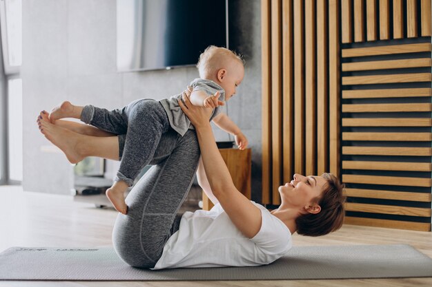 La giovane madre pratica lo yoga con il figlio piccolo sul tappetino