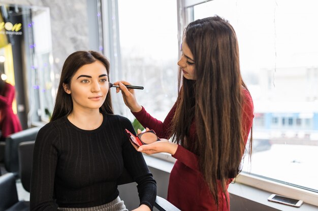 La giovane modella con grandi occhi sta avendo una procedura di trucco