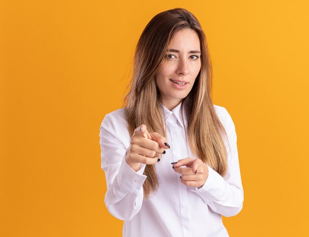 La giovane ragazza abbastanza caucasica sicura indica la macchina fotografica con due mani