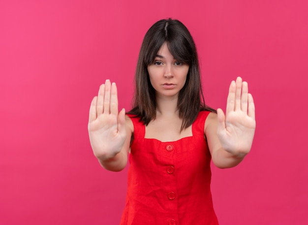 La giovane ragazza caucasica sicura ferma il gesto con entrambe le mani su fondo rosa isolato con lo spazio della copia