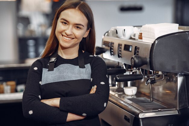 La giovane ragazza di barista fa il caffè e sorride