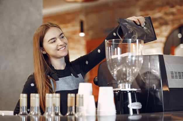 La giovane ragazza di barista fa il caffè e sorride