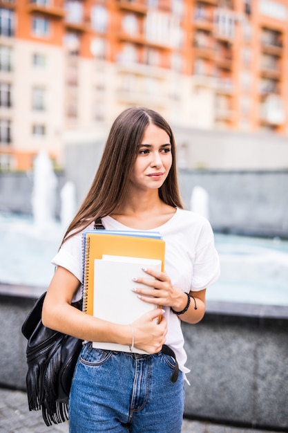 La giovane studentessa di talento si è vestita in abbigliamento casual che cammina intorno alla città. Donna attraente del brunette che gode del tempo libero all'aperto