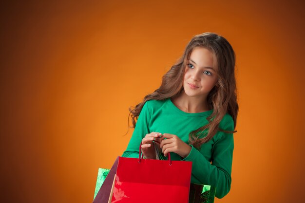 La graziosa bambina allegra con le borse della spesa