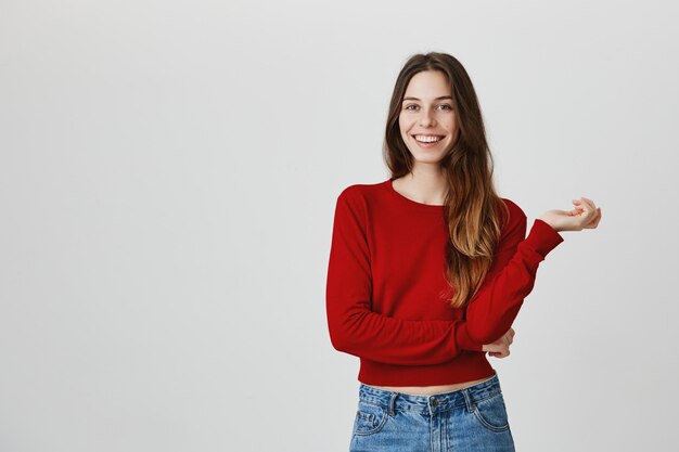 La macchina fotografica a trentadue denti sorridente della giovane donna attraente, sembra entusiasta