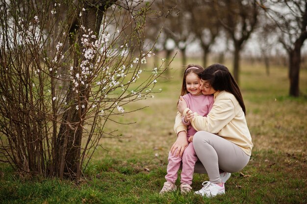 La madre abbraccia la figlia della sua bambina nel giardino di primavera