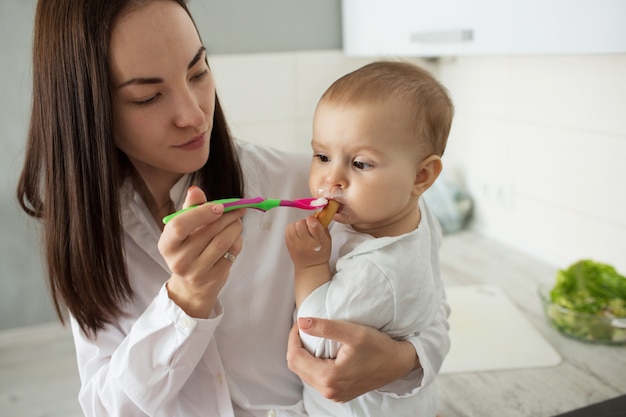 La madre alimenta il bambino sveglio con il cucchiaio