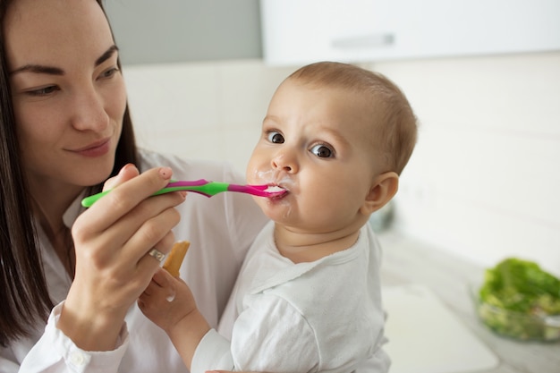 La madre alimenta il bambino sveglio con il cucchiaio