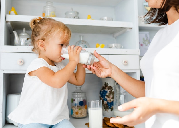 La madre che tiene un bicchiere di latte fer sua figlia