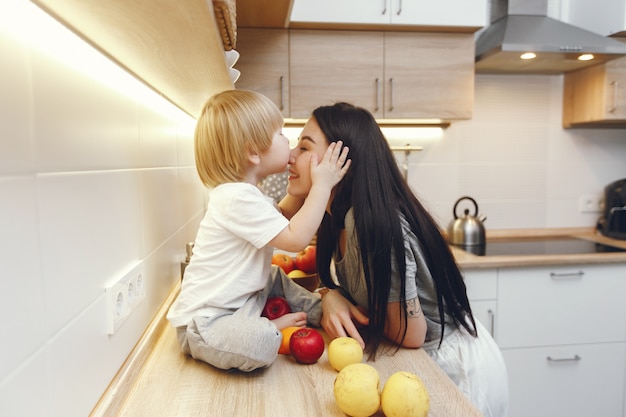 La madre con il piccolo figlio che mangia la frutta in una cucina