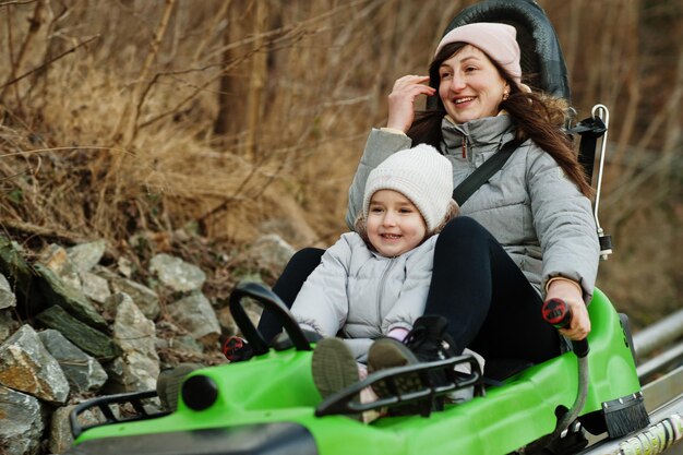 La madre con la figlia guida la slitta elettrica sulle rotaie