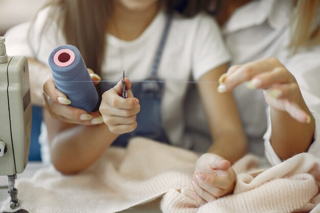 La madre con la piccola figlia cuce i vestiti nella fabbrica