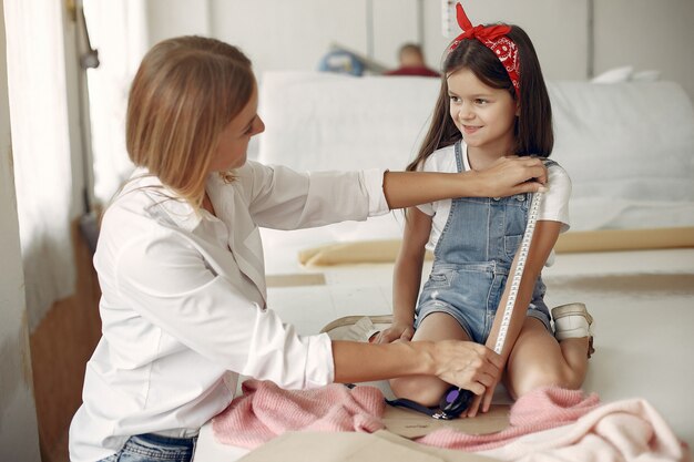 La madre con la piccola figlia misura il tessuto per cucire