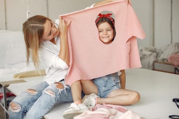 La madre con la piccola figlia misura il tessuto per cucire