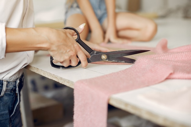 La madre con la piccola figlia misura il tessuto per cucire