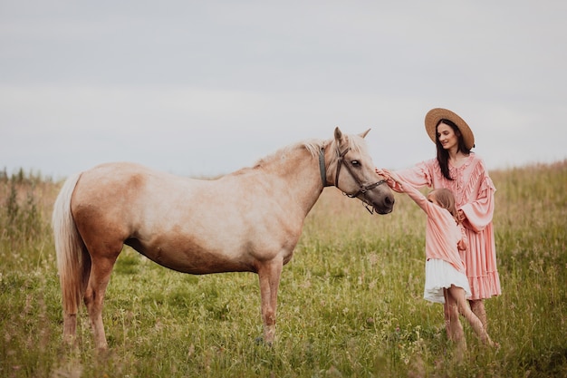 La madre e la figlia stanno sul campo prima di un cavallo