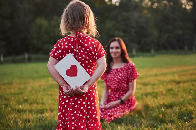 La madre gioca con sua figlia sulla strada nel parco al tramonto