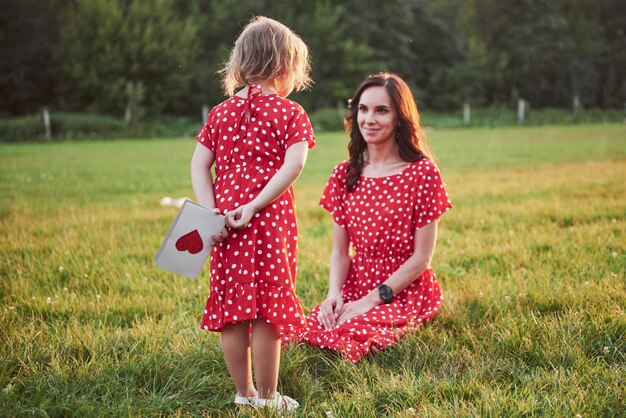 La madre gioca con sua figlia sulla strada nel parco al tramonto