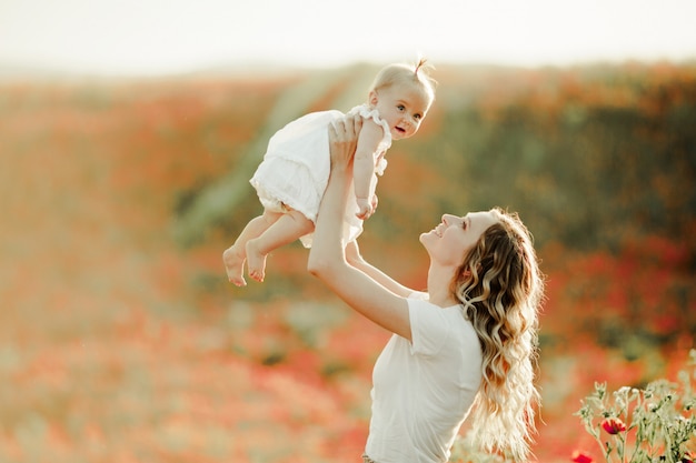 La madre tiene il suo bambino in altezza sul campo di papaveri