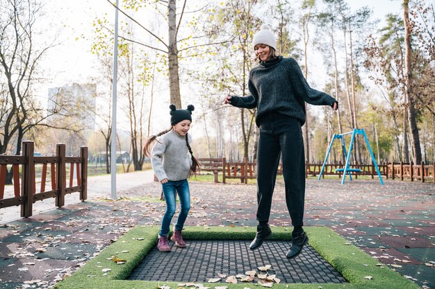 La mamma e sua figlia che saltano insieme sul trampolino in autunno parcheggiano