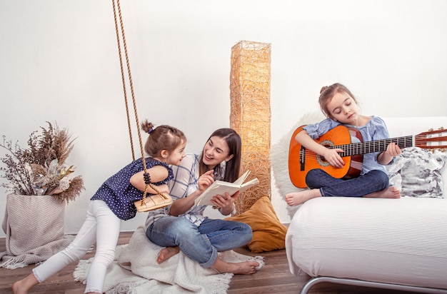 La mamma gioca con le sue figlie a casa. Lezioni su uno strumento musicale, chitarra. Il concetto di amicizia e famiglia dei bambini.